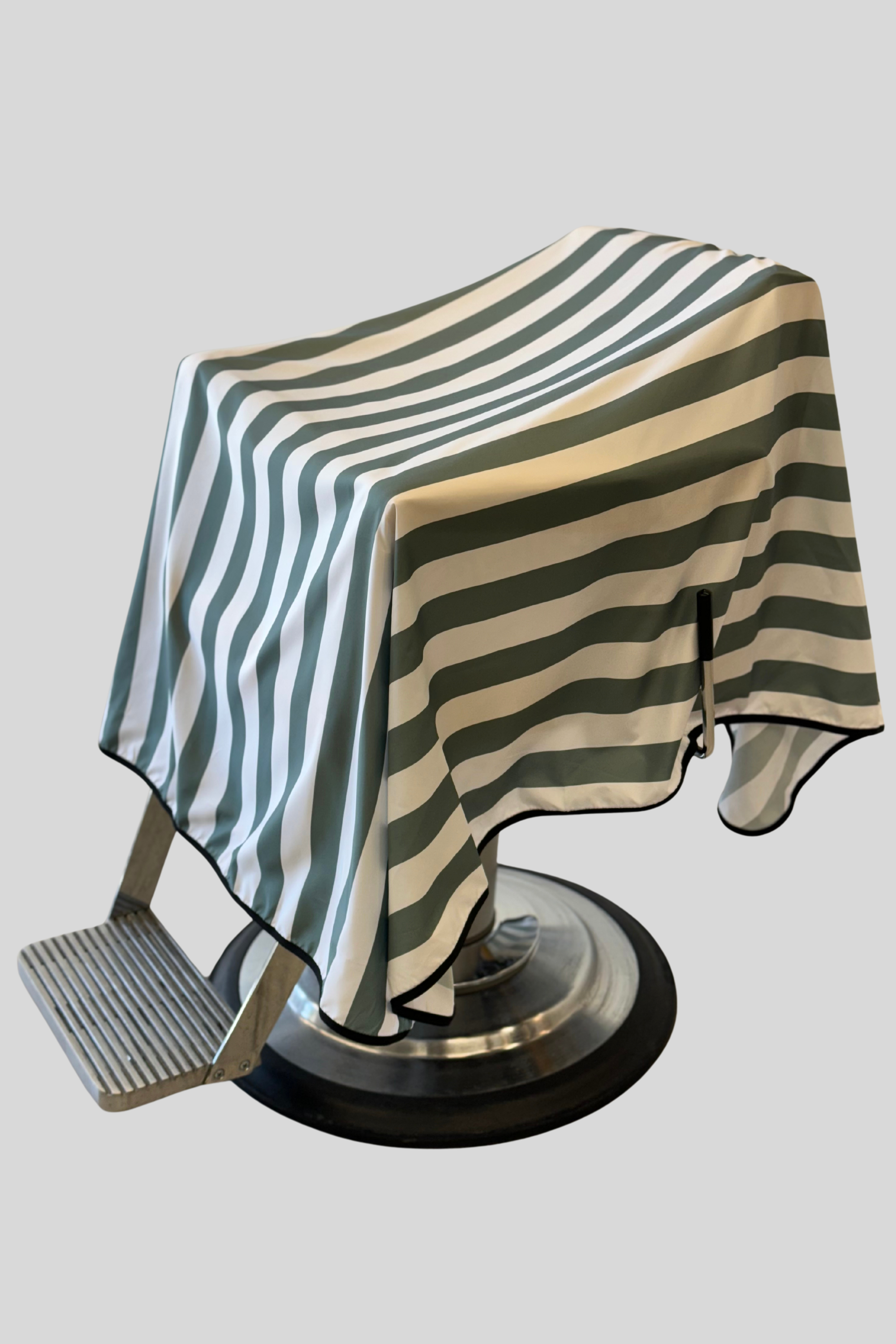 product photo of striped green banded barber cape draped on barber chair