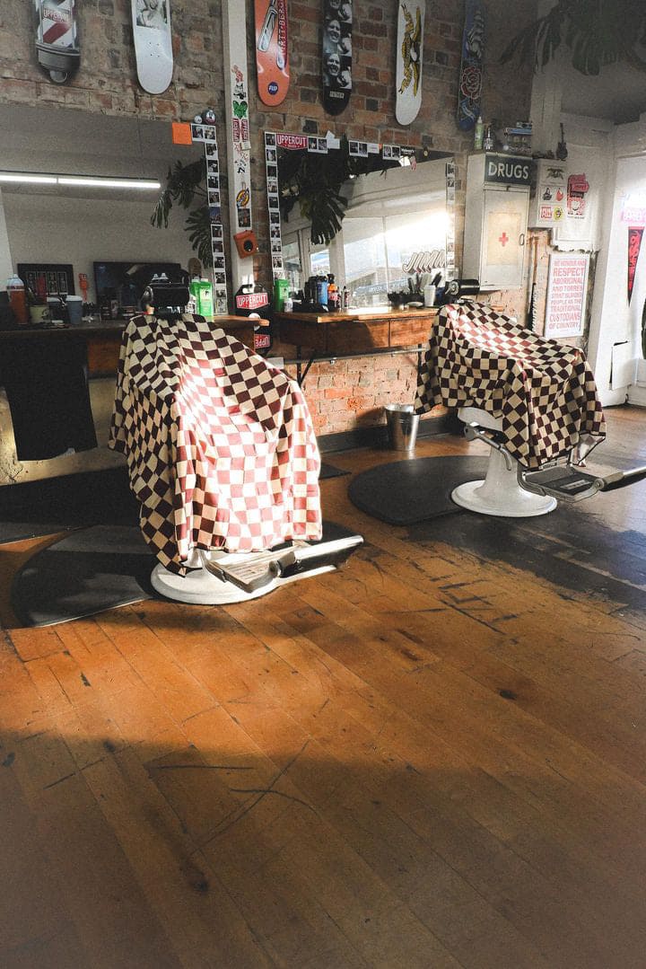 Check Capes draped over two barber chairs inside Jimmy's Barbershop in Australia. 