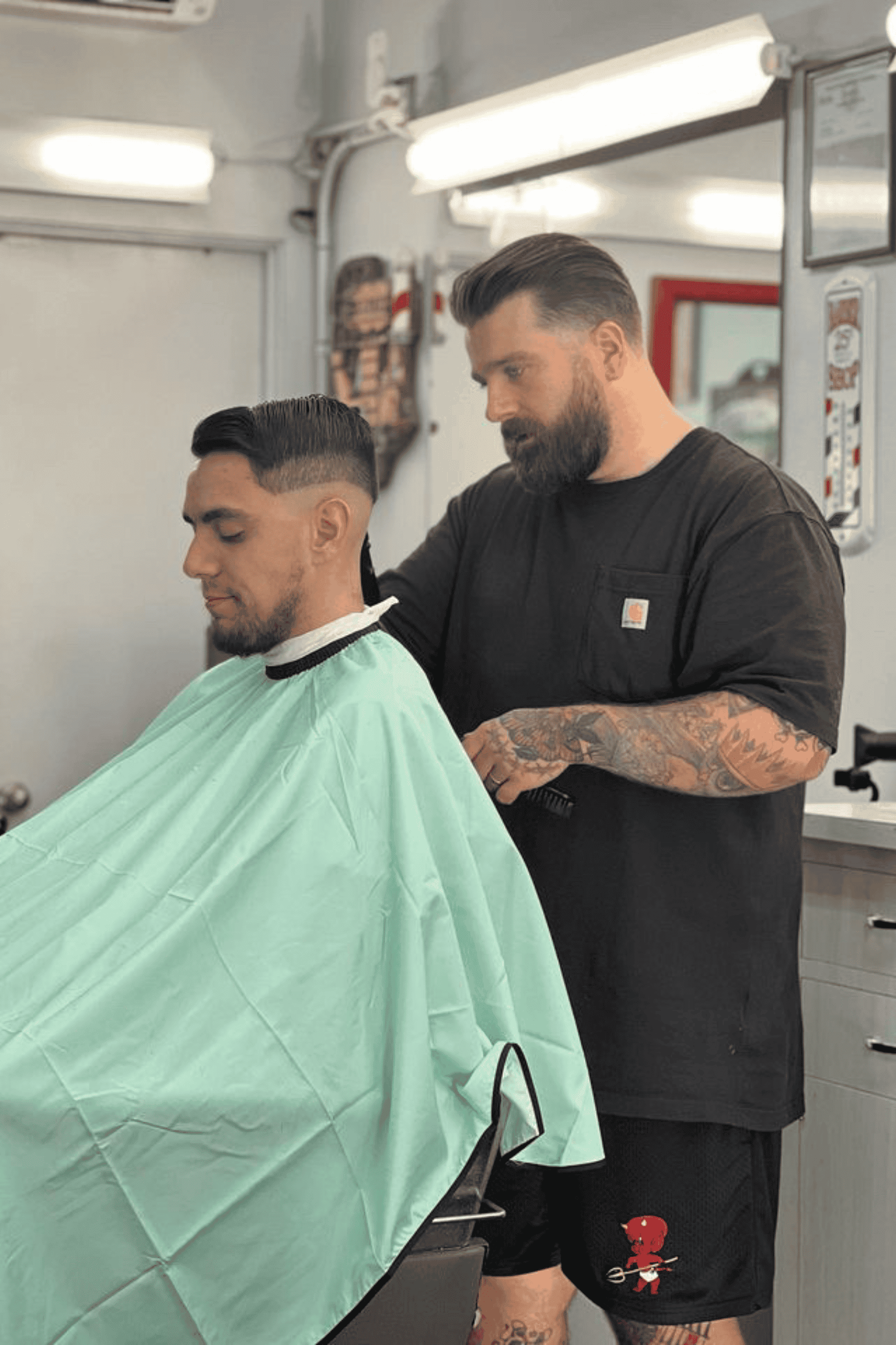 sage colored barber cutting cape draped on barber chair inside a barbershop