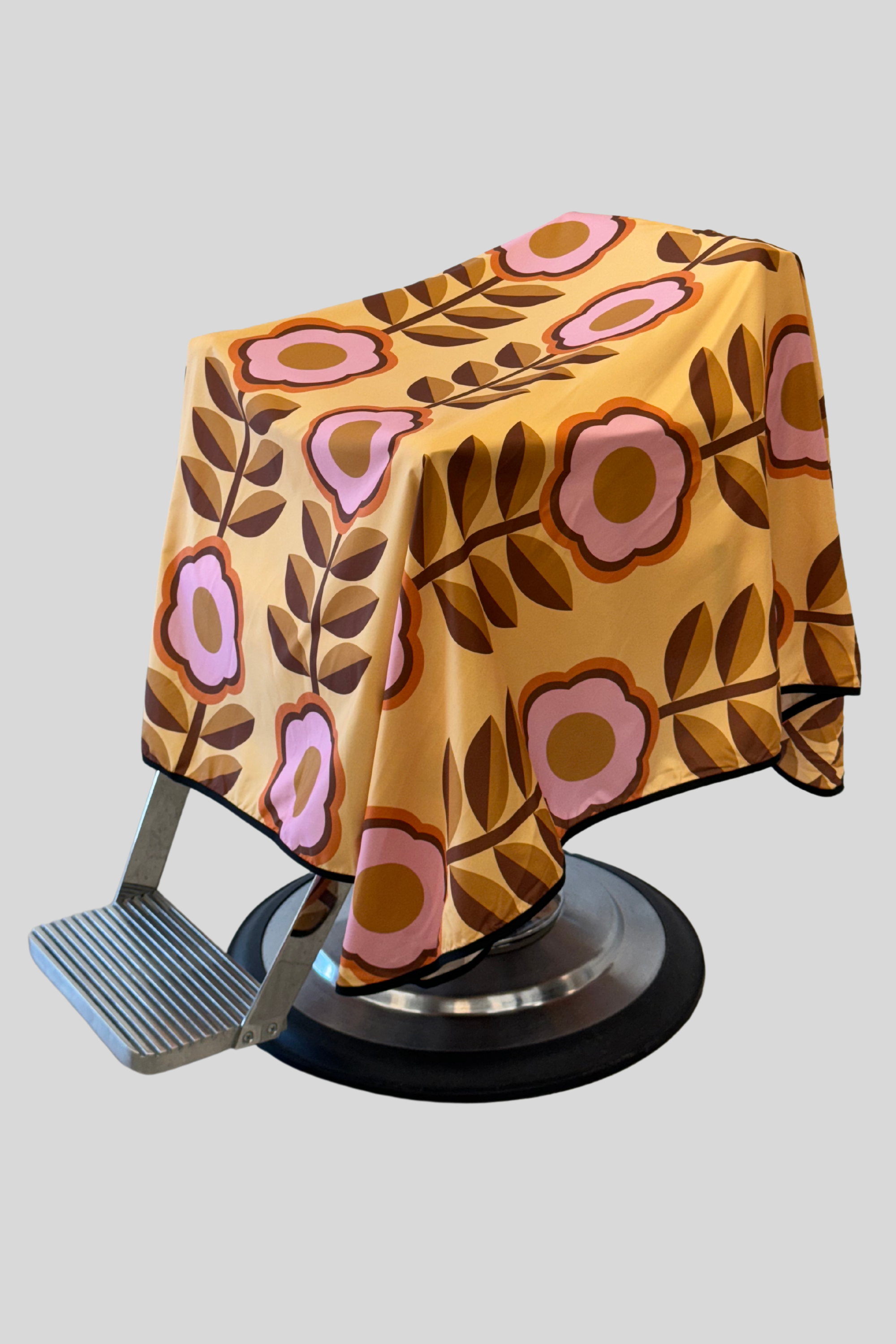 retro floral barber cape with a mustard yellow background and pink flowers
