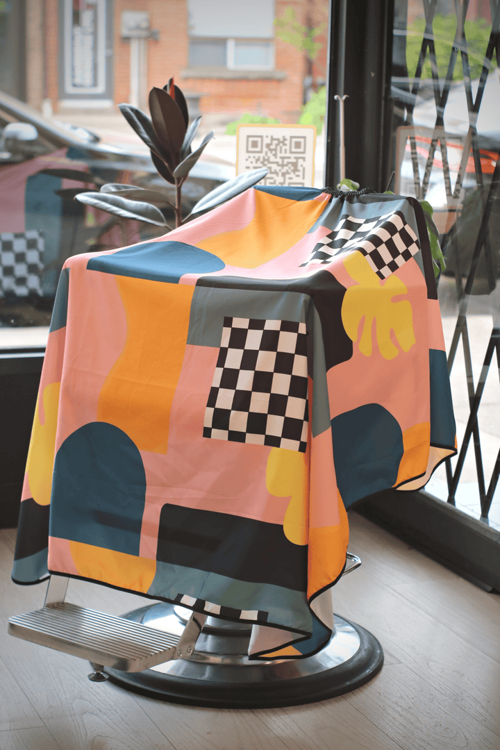 Full view of Century Cape inside barbershop and draped over a barber chair.