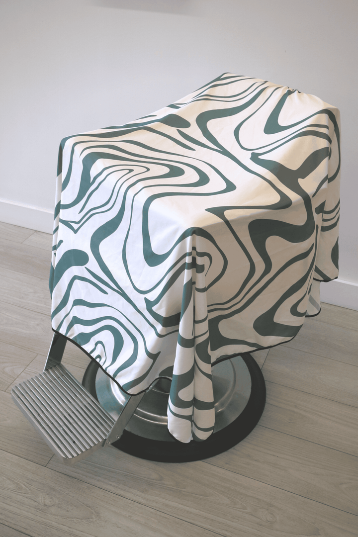 Angled view of the Aurora Cape, a white and green barber cape by High Top Capes.